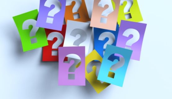 13 colourful cardboards, each with a question mark cut-out in the middle, overlap each other in a pile