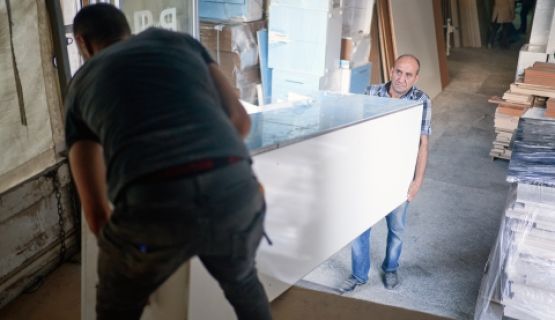 Two men lift heavy furniture off a truck