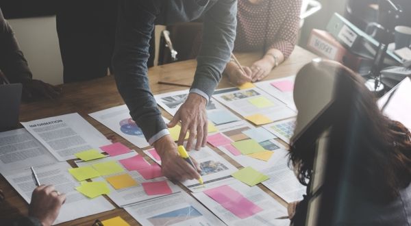 Co-workers strategize at table with sticky notes