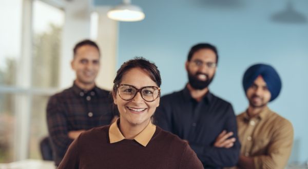 Workers of various ethnicities pose happily with their work team